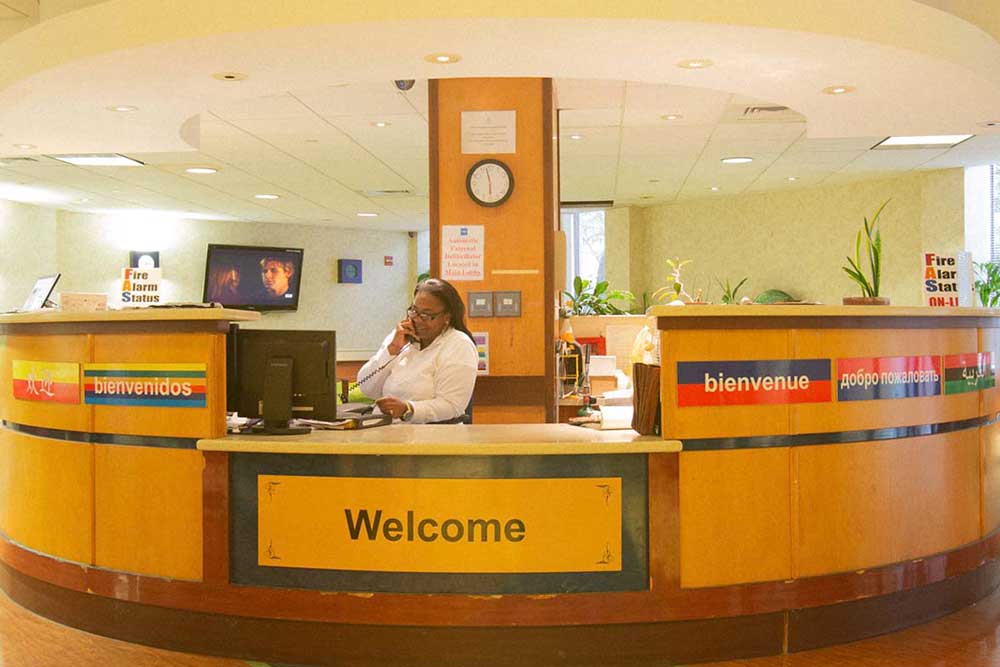 Admissions desk at Downtown Brooklyn Nursing and Rehabilitation Center, welcome signs in multiple languages.