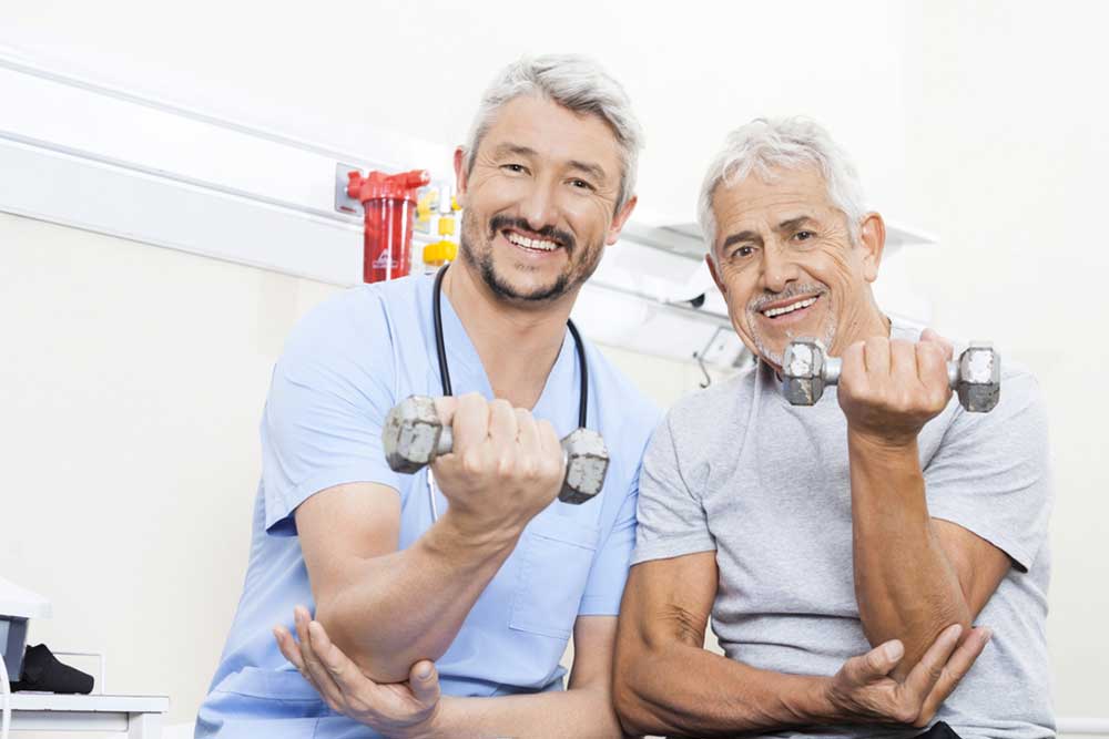 Happy Physiotherapist And Senior Patient Lifting Dumbbells