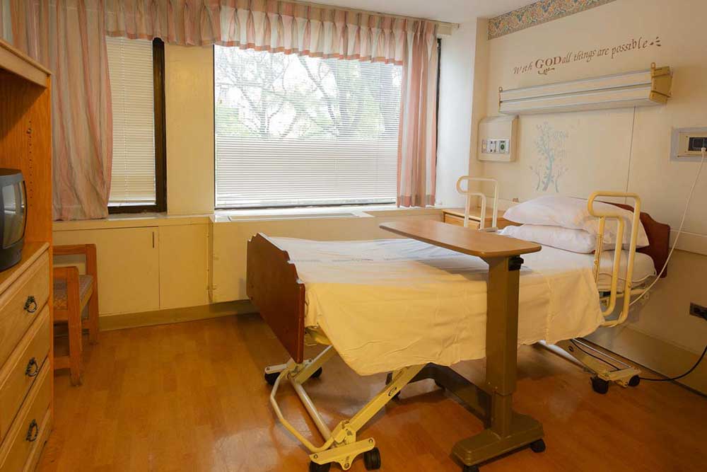Patient room with hospital bed, television, and furniture at Downtown Brooklyn facility.