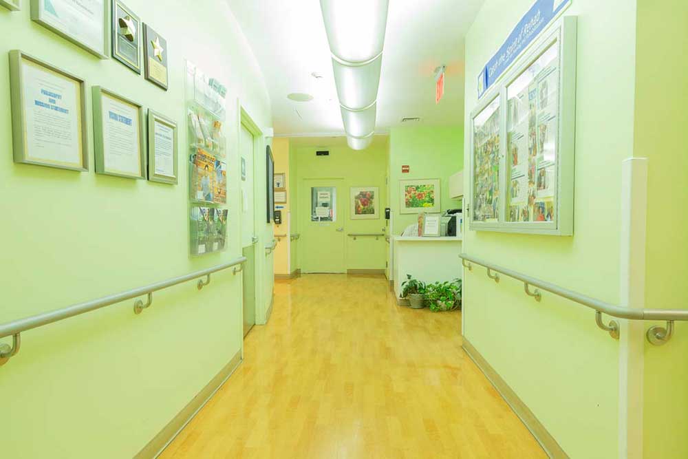Long corridor with wall decorations and bright lights at Downtown Brooklyn Nursing and Rehabilitation Center.